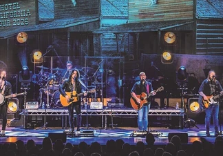 Four men on stage performing to a crowd.