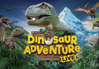 T-Rex in foreground surrounded by trees and mountains in the background.