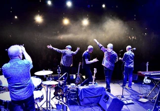 All five band members on stage facing towards the audience away from the camera.