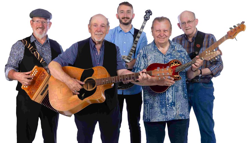 Five men, all holding musical instruments, smiling.