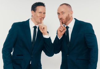 Two men in black suits with fingers pointing to their lips.